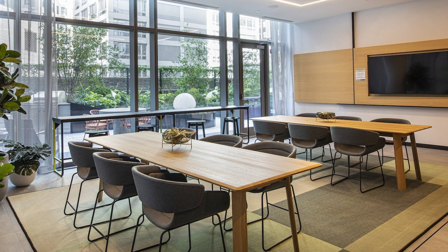 Spacious resident lounge with co-working tables and outdoor patio access at Millie on Michigan in Chicago