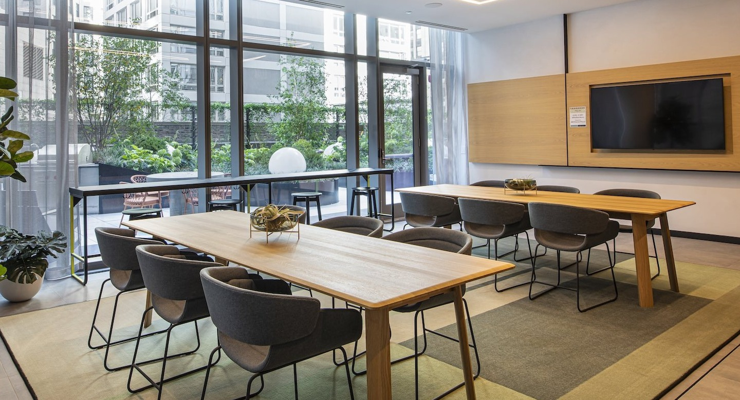 Spacious resident lounge with co-working tables and outdoor patio access at Millie on Michigan in Chicago