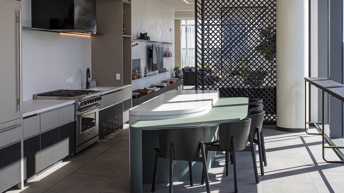 Modern resident lounge kitchen and bar area with tall windows at Millie on Michigan apartments in Chicago