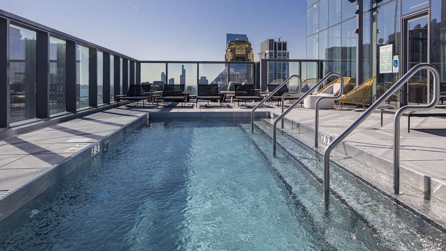 Sparkling rooftop pool area with lounge chairs and city skyline views at Millie on Michigan in Chicago