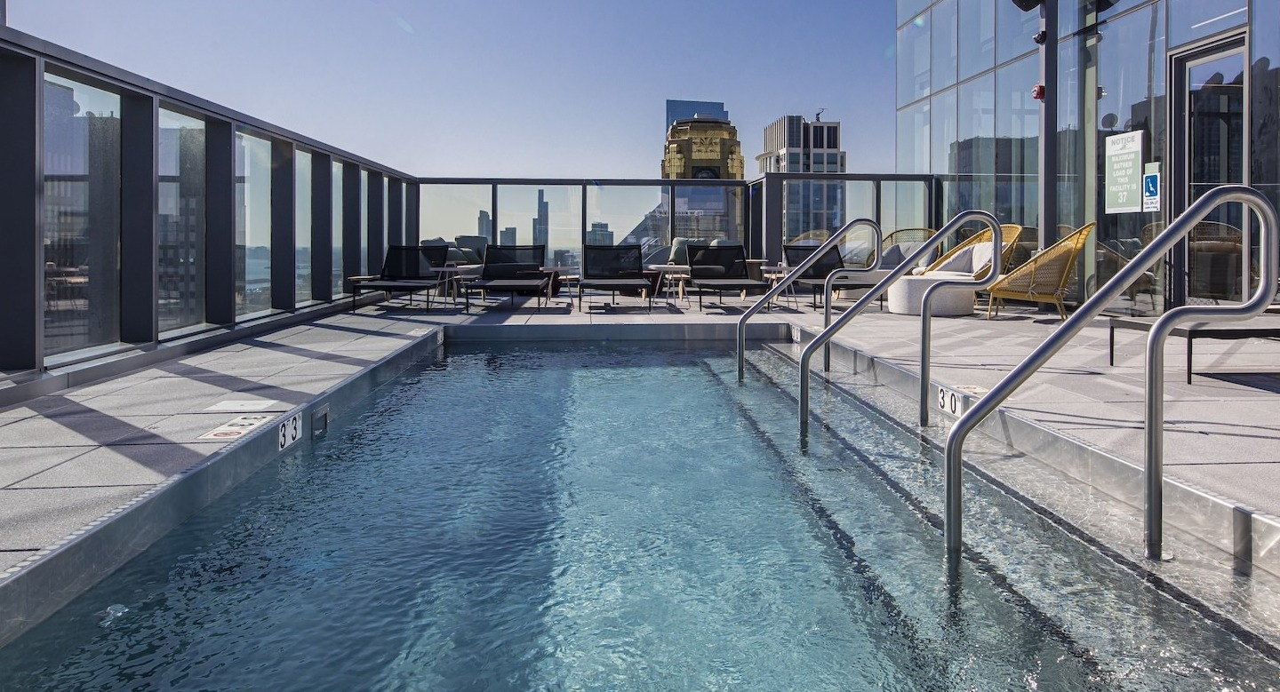 Sparkling rooftop pool area with lounge chairs and city skyline views at Millie on Michigan in Chicago