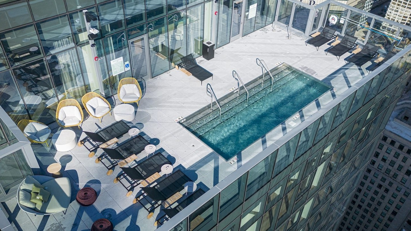 Stunning rooftop pool deck with lounge chairs and breathtaking city skyline views at Millie on Michigan Chicago