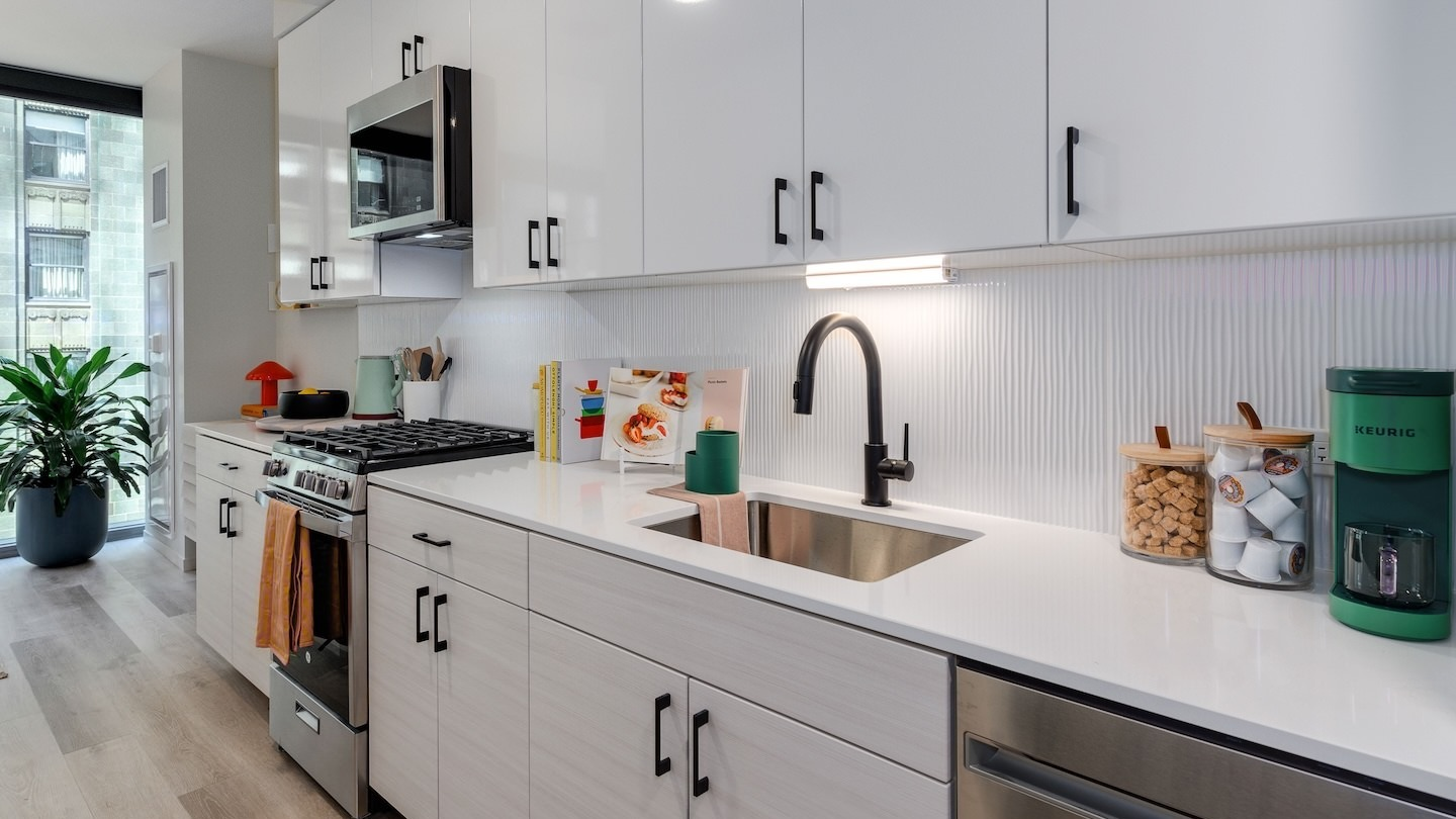 Sleek apartment kitchen with white cabinets, stainless steel appliances, and a modern backsplash at Millie on Michigan Chicago