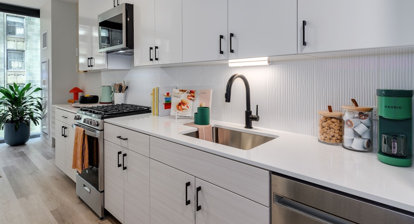 Sleek apartment kitchen with white cabinets, stainless steel appliances, and a modern backsplash at Millie on Michigan Chicago