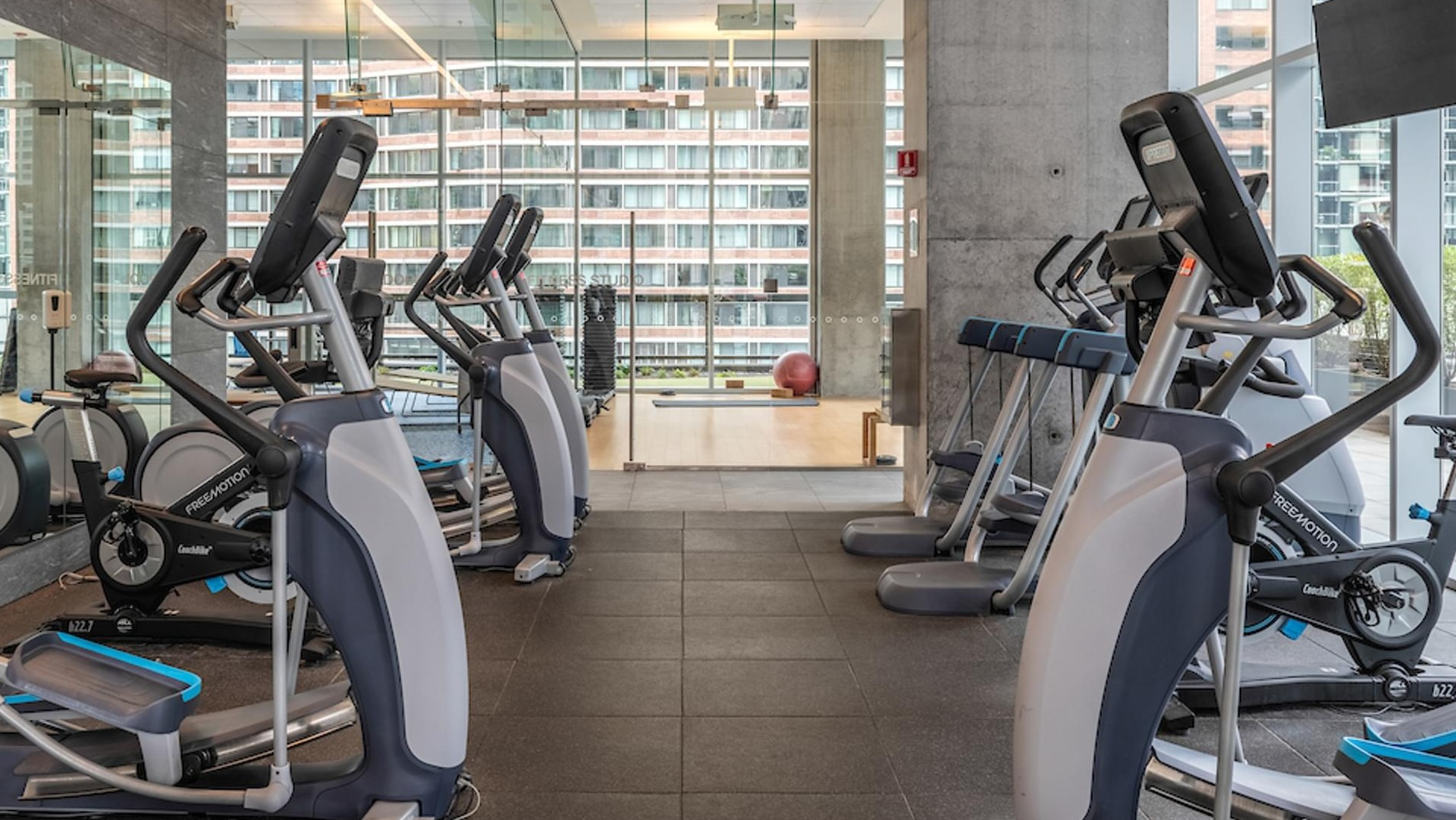 Fitness center with treadmills, ellipticals, and large windows overlooking the city at Optima Signature apartments in Chicago