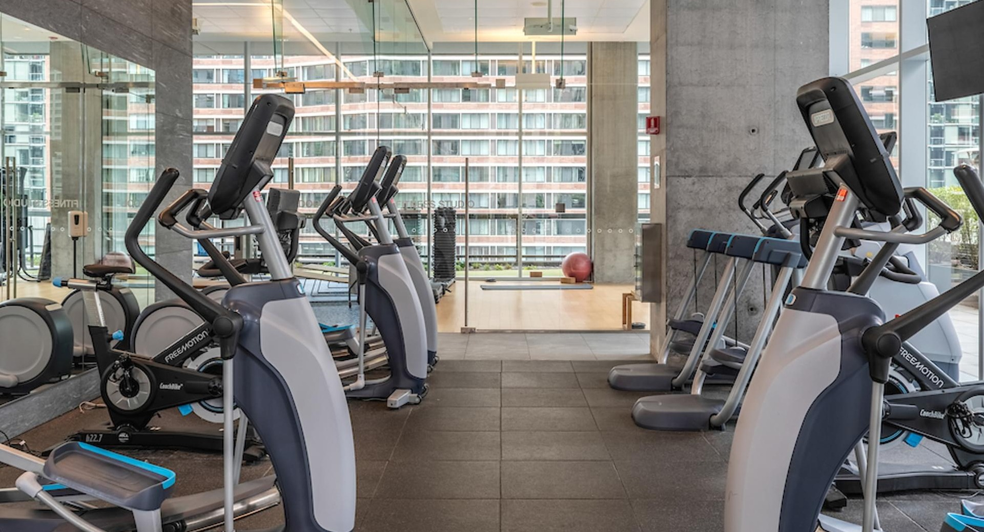 Fitness center with treadmills, ellipticals, and large windows overlooking the city at Optima Signature apartments in Chicago