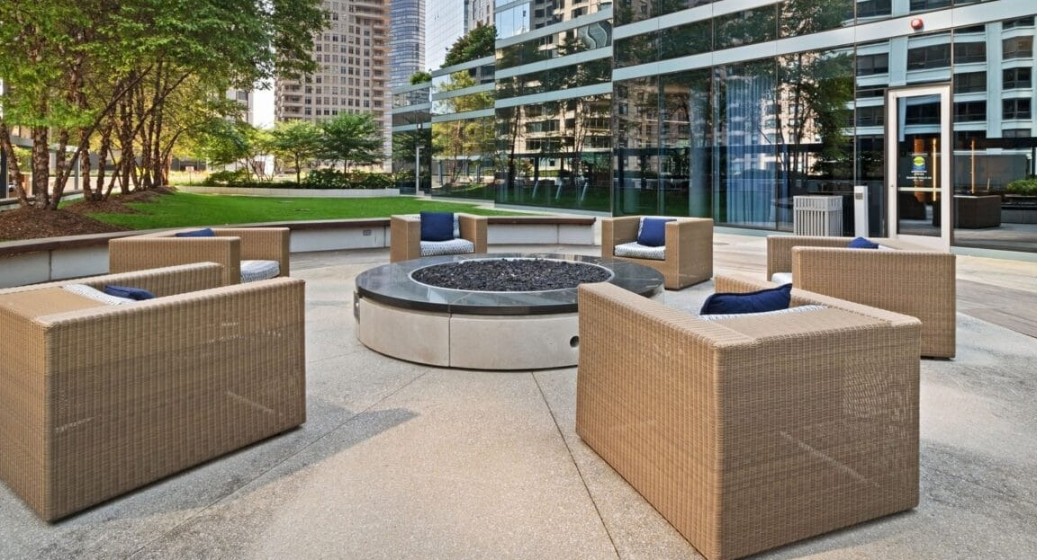 Inviting outdoor fire pit lounge at Moment Apartments in Chicago, with comfortable seating surrounded by trees and modern buildings