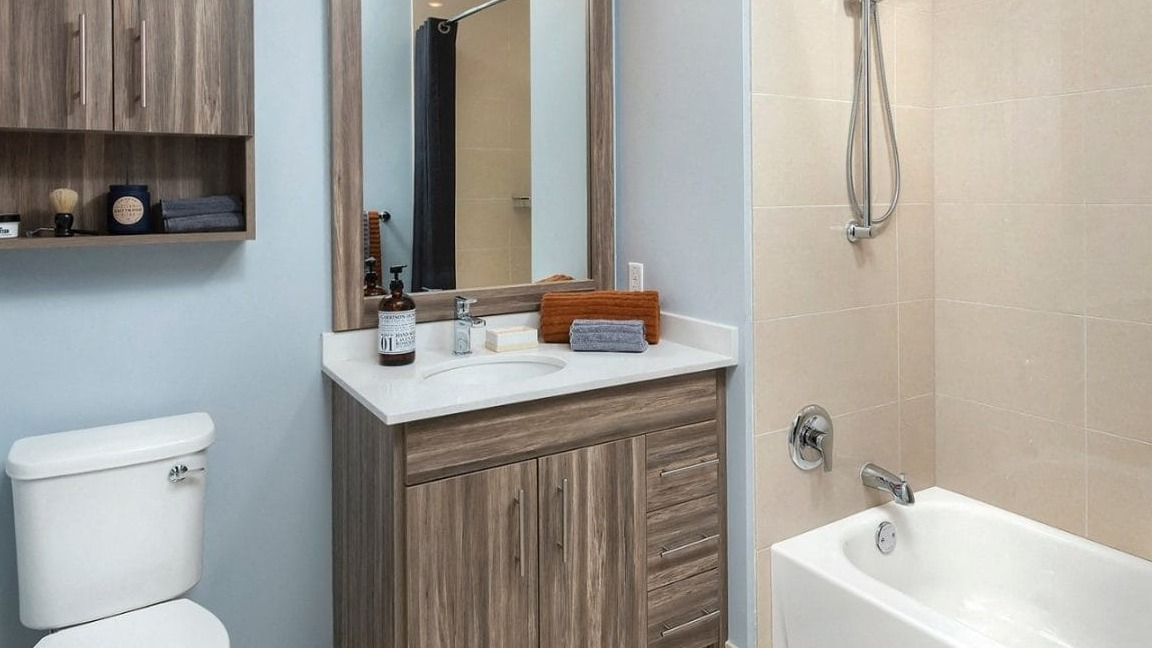 Modern apartment bathroom at Moment Apartments in Chicago, featuring a wood-grain vanity, stylish mirror, and a bathtub with a shower