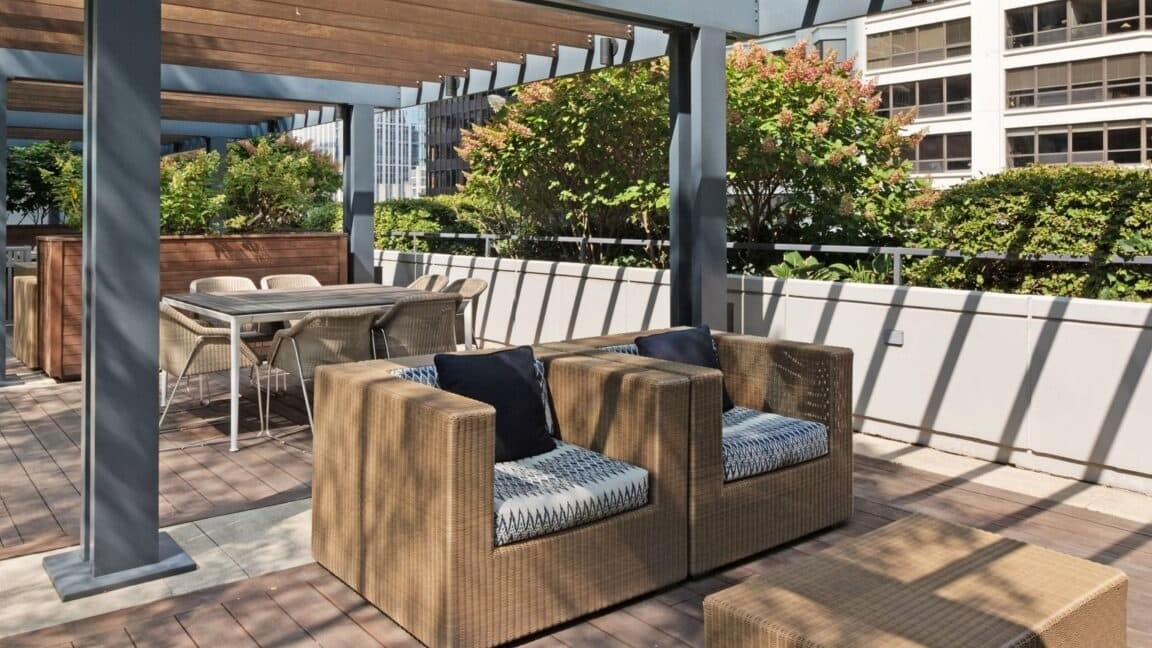 Stylish outdoor seating area under a modern pergola at Moment Apartments in Chicago, perfect for relaxation amidst lush greenery