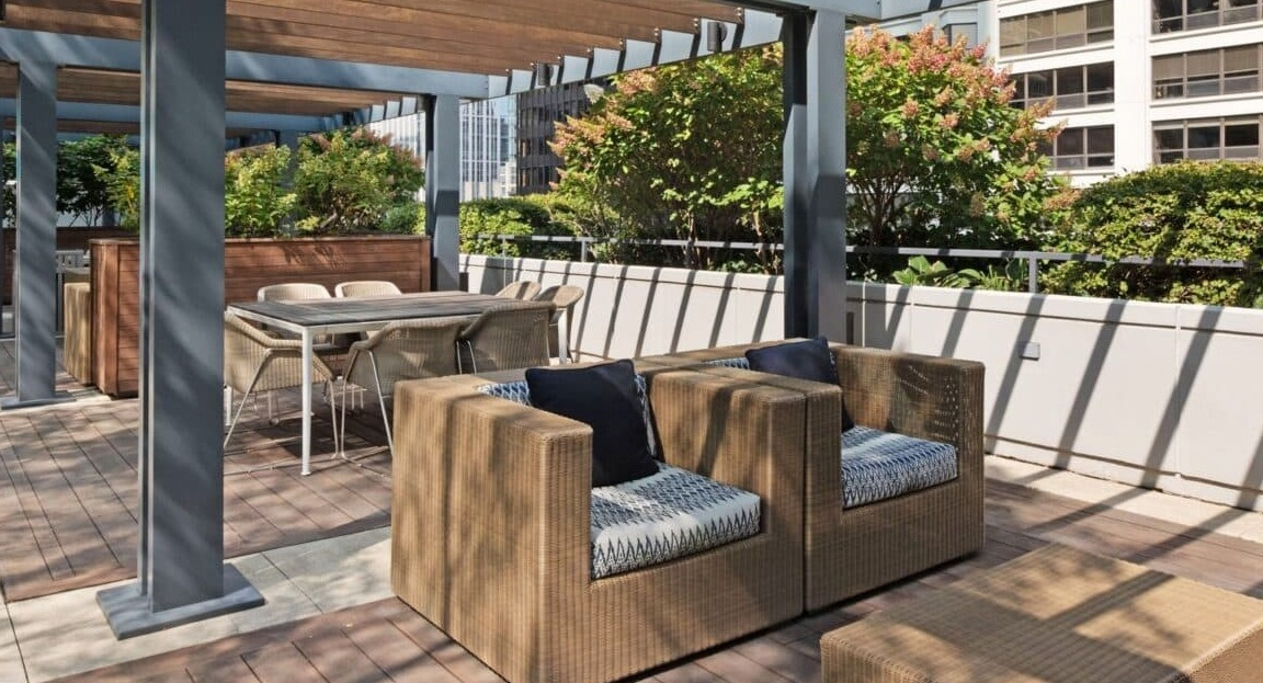 Stylish outdoor seating area under a modern pergola at Moment Apartments in Chicago, perfect for relaxation amidst lush greenery