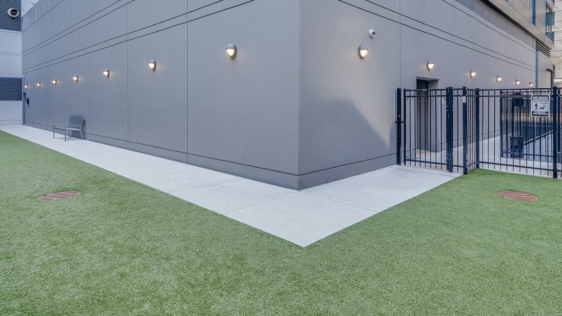 An outdoor pet-friendly dog run area with artificial turf and secure fencing at Moment Apartments in Chicago