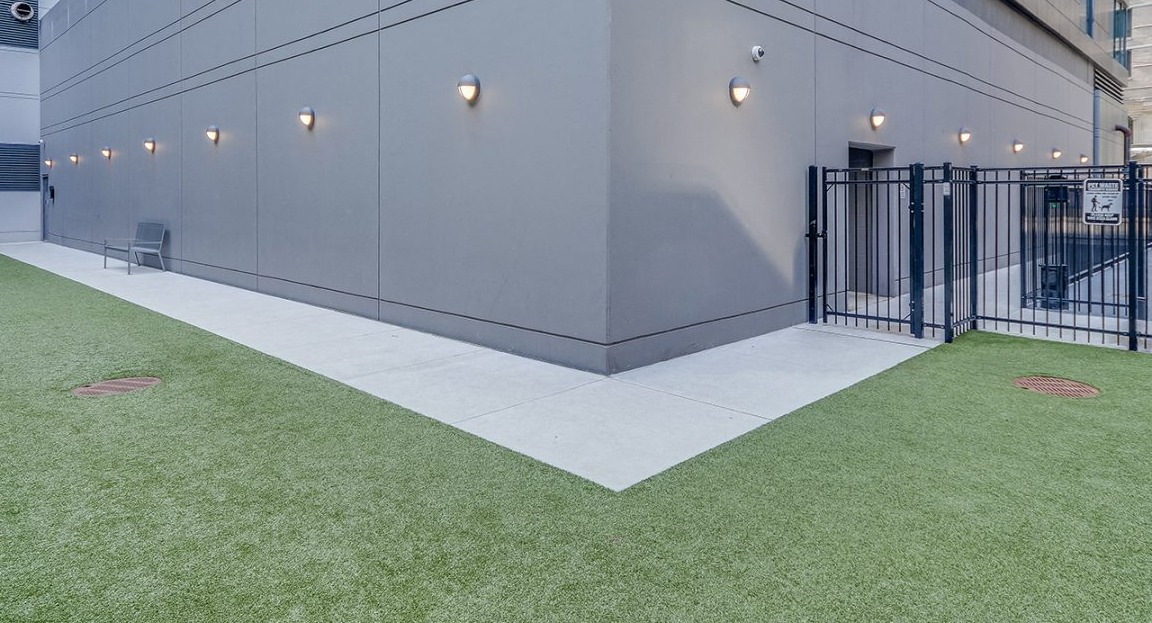 An outdoor pet-friendly dog run area with artificial turf and secure fencing at Moment Apartments in Chicago