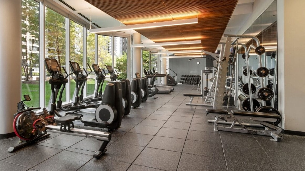 A state-of-the-art fitness center with a variety of exercise equipment and large windows at Moment Apartments in Chicago
