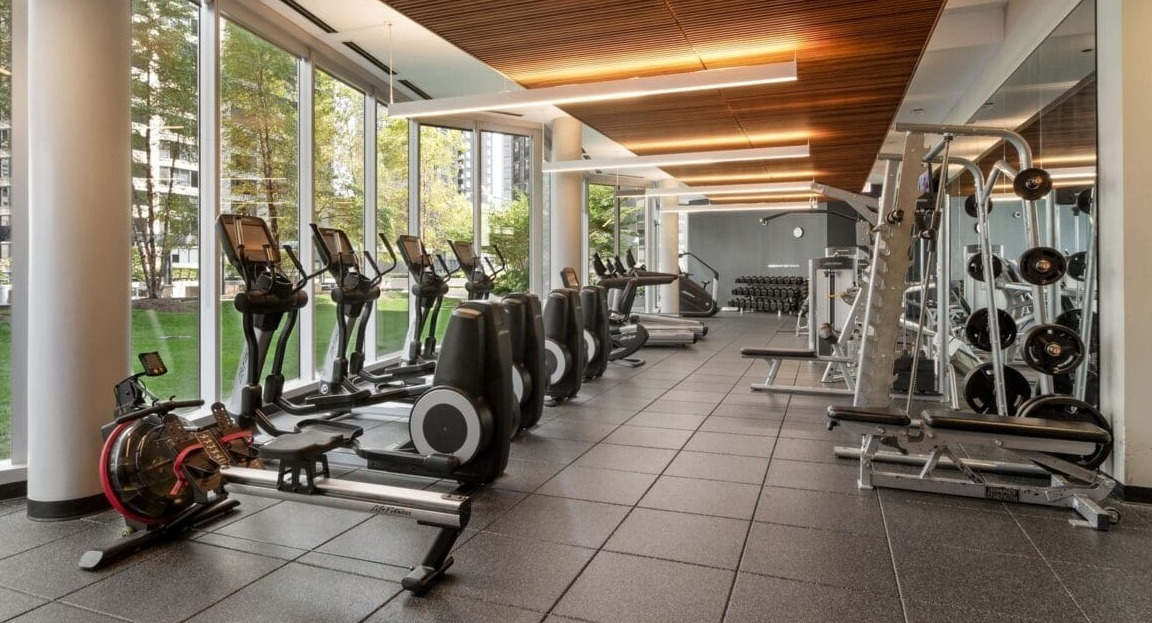 A state-of-the-art fitness center with a variety of exercise equipment and large windows at Moment Apartments in Chicago