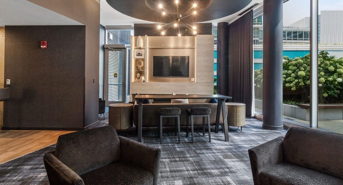 A stylish TV lounge area with comfortable armchairs and a unique ceiling fixture at Moment Apartments in Chicago