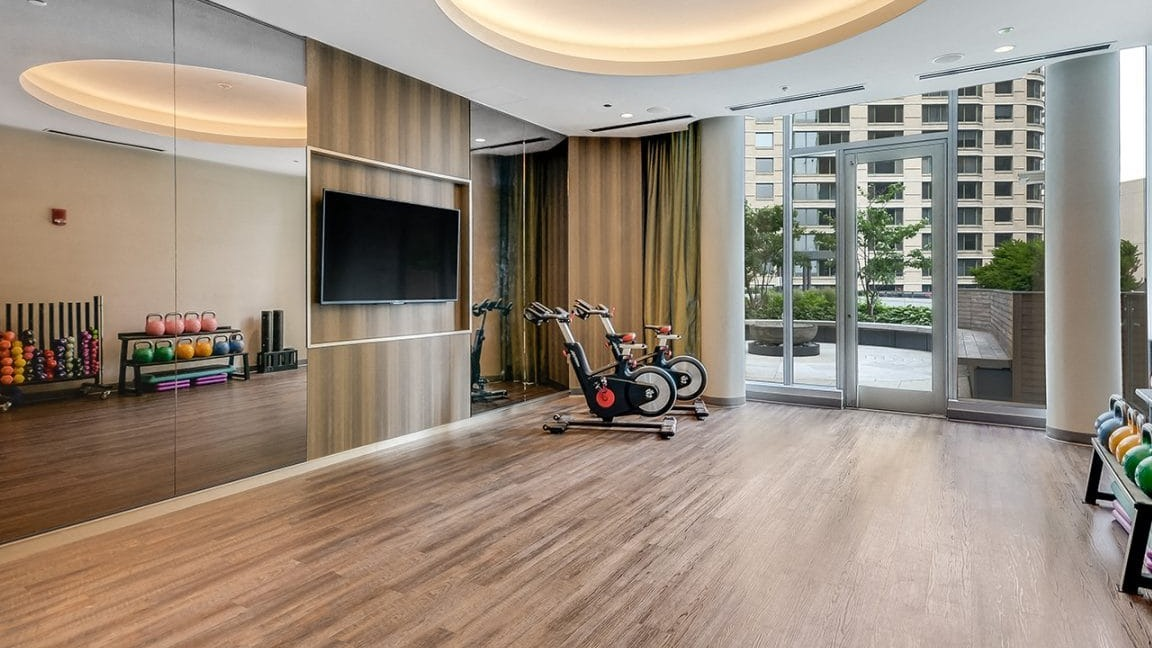 Spacious yoga and fitness studio at Moment Apartments in Chicago, equipped with exercise bikes, weights, and large mirrors
