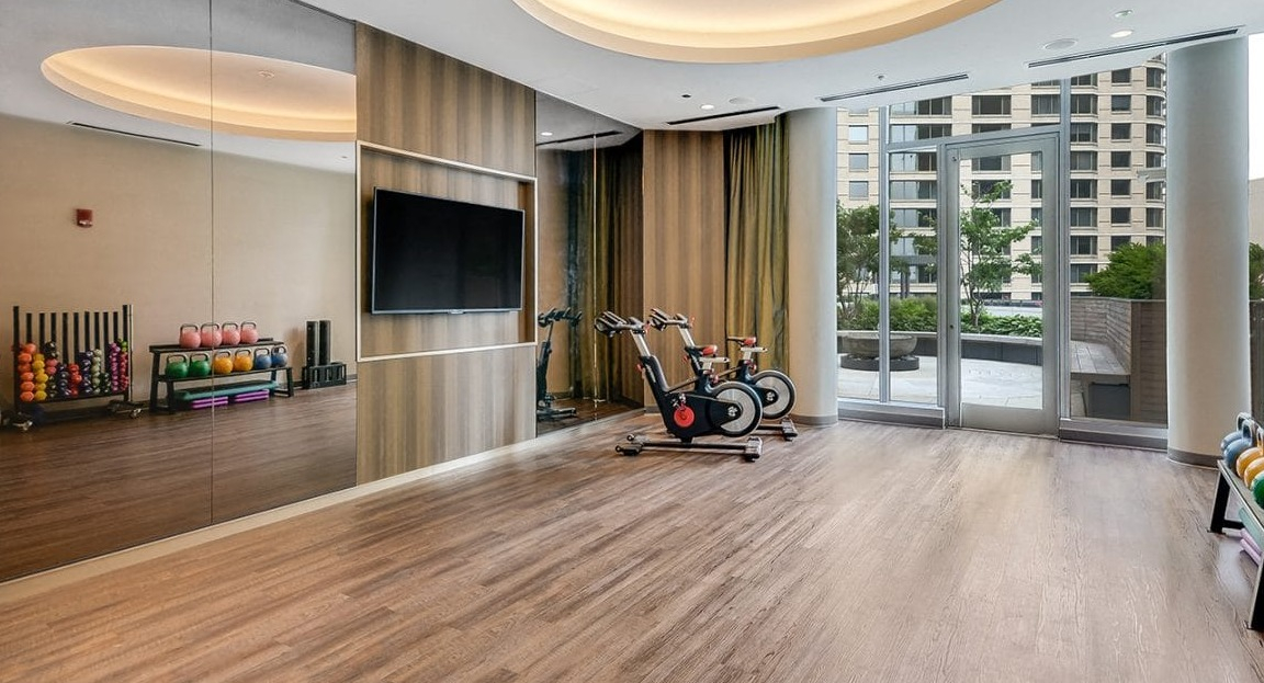 Spacious yoga and fitness studio at Moment Apartments in Chicago, equipped with exercise bikes, weights, and large mirrors