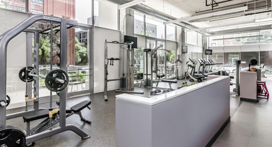 Well-equipped fitness center with various weight training machines and free weights, bathed in natural light at Mondial River West in Chicago