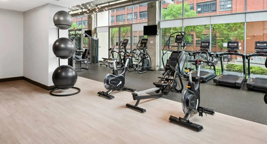 Modern gym with diverse exercise equipment, including bikes, treadmills, and a smart mirror, at Mondial River West in Chicago