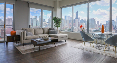 Expansive living and dining room with a large sectional sofa, stylish dining set, and panoramic city views at Mondial River West in Chicago