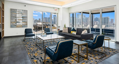 Stylish resident lounge with comfortable seating, a fireplace, and large windows leading to an outdoor terrace at Mondial River West in Chicago