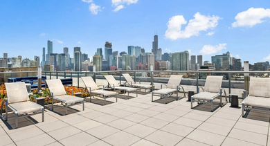 Wide rooftop terrace showcasing a panoramic Chicago cityscape, complete with lounge chairs and decorative planters at Mondial River West