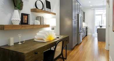 Stylish home office and kitchen hallway at Monroe Aberdeen Place in Chicago, featuring a wooden desk, floating shelves, and modern kitchen appliances