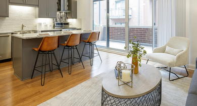 Bright apartment kitchen at Monroe Aberdeen Place in Chicago, featuring a large island, stylish pendant lights, and an open view into the living room