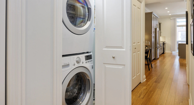 Convenient in-unit laundry closet at Monroe Aberdeen Place in Chicago, featuring stacked washer and dryer for easy access