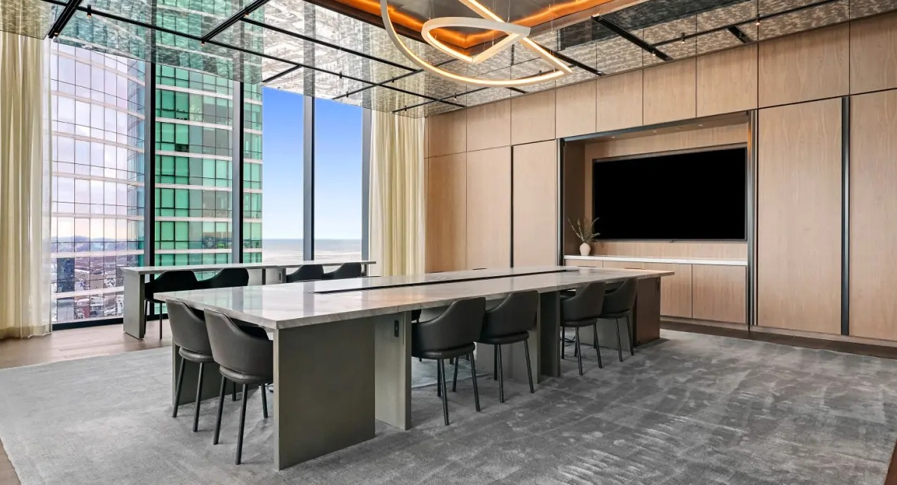 Luxurious conference room at NEMA Chicago, featuring a large table, modern seating, and stunning city views through expansive windows