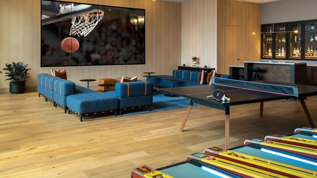 Vibrant game room and lounge at NEMA Chicago, featuring a large screen for sports, a ping pong table, and comfortable seating
