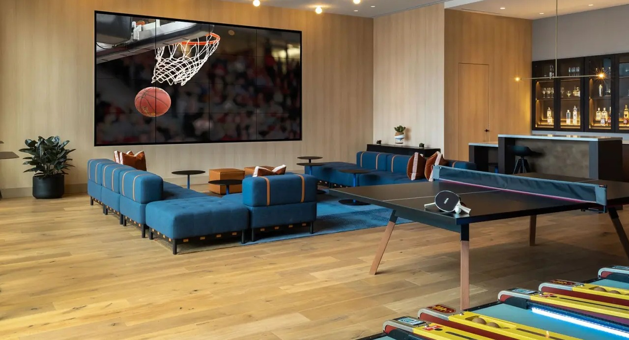 Vibrant game room and lounge at NEMA Chicago, featuring a large screen for sports, a ping pong table, and comfortable seating