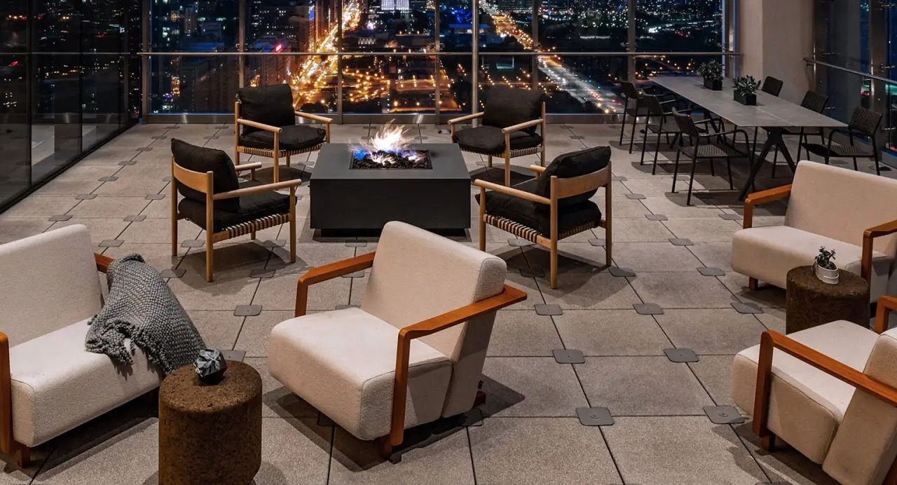 Stunning rooftop terrace at NEMA Chicago at night, featuring a warm fire pit, comfortable seating, and dazzling city skyline lights