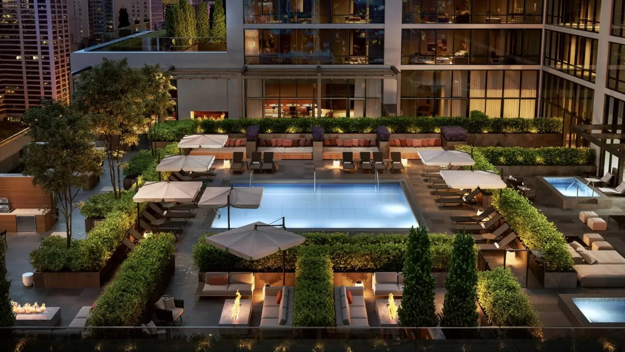 Luxurious rooftop pool and patio at NEMA Chicago, featuring ample lounge seating, manicured landscaping, and stunning city views