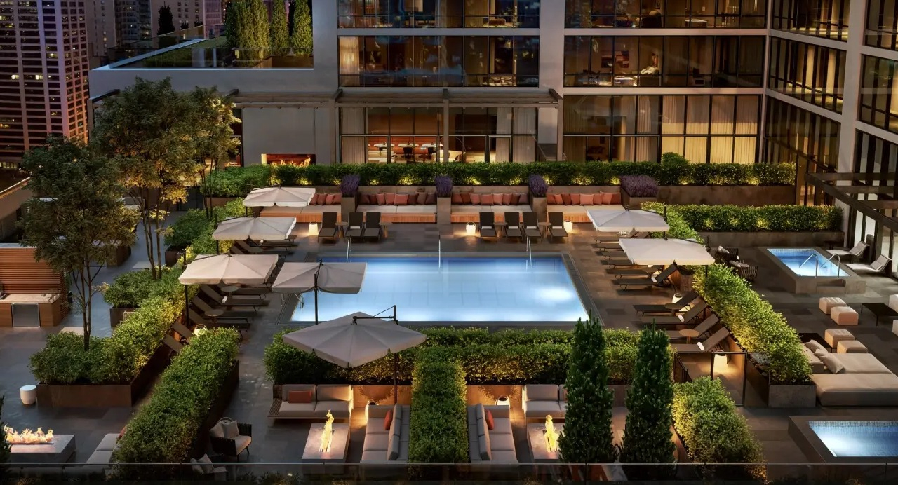 Luxurious rooftop pool and patio at NEMA Chicago, featuring ample lounge seating, manicured landscaping, and stunning city views