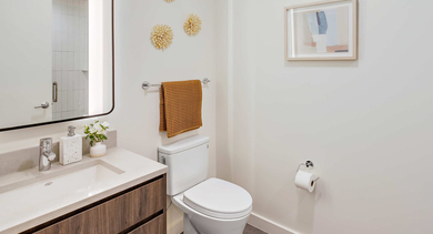 Bright apartment bathroom at Nevele22 in Chicago, featuring a modern vanity with a large mirror, toilet, and stylish decor