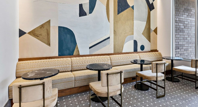 Vibrant resident lounge at Nevele22 in Chicago, featuring a striking abstract art wall, comfortable banquette seating, and modern tables