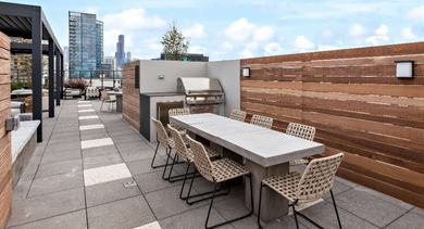 Expansive rooftop patio at Nevele22 in Chicago, featuring a modern grilling station and a large dining table with city views