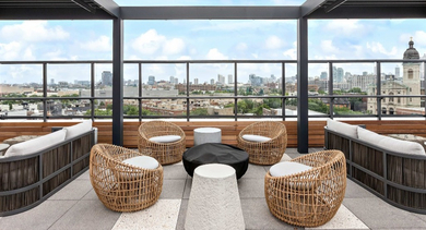 Chic rooftop lounge area at Nevele22 in Chicago, featuring comfortable woven seating under a stylish pergola and panoramic city views