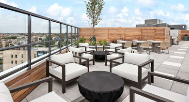 Expansive rooftop terrace at Nevele22 in Chicago, featuring diverse seating, green planters, and open skies for outdoor enjoyment
