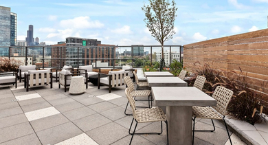 Spacious rooftop patio at Nevele22 in Chicago, offering various seating areas, lush plants, and captivating city skyline views