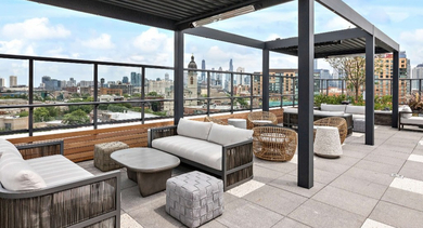 Inviting rooftop lounge at Nevele22 in Chicago, featuring shaded seating areas under a modern pergola and panoramic city views
