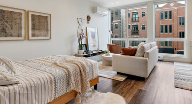 Stylish studio apartment at Nevele22 in Chicago, featuring a comfortable bed, inviting living area, and a modern kitchen