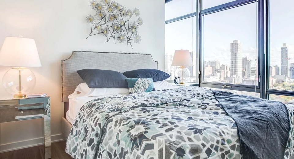 Elegant bedroom with a comfortable bed, chic decor, and expansive cityscape views at NEXT Apartments in Chicago