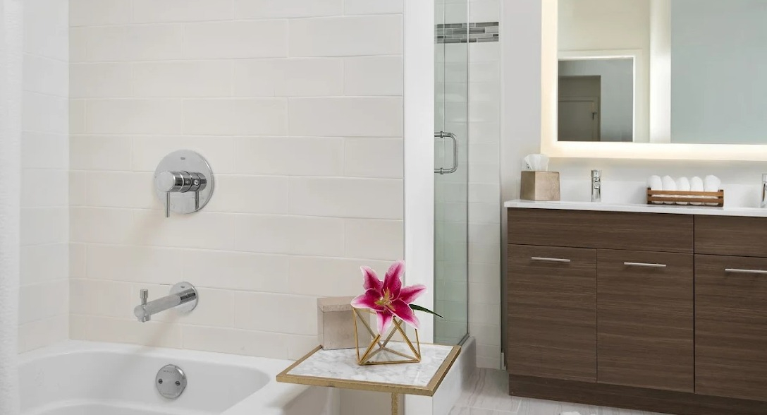 Modern bathroom with a clean design, white tile bathtub, glass shower, and illuminated mirror at NEXT Apartments in Chicago