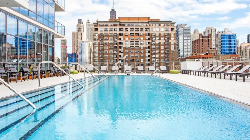 Inviting rooftop swimming pool with lounge chairs and panoramic views of the Chicago skyline at NEXT Apartments
