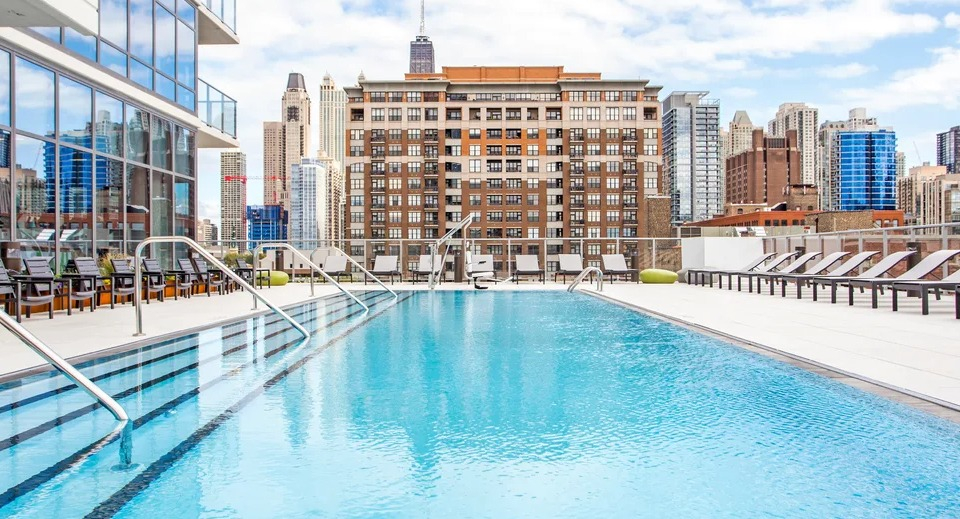 Inviting rooftop swimming pool with lounge chairs and panoramic views of the Chicago skyline at NEXT Apartments