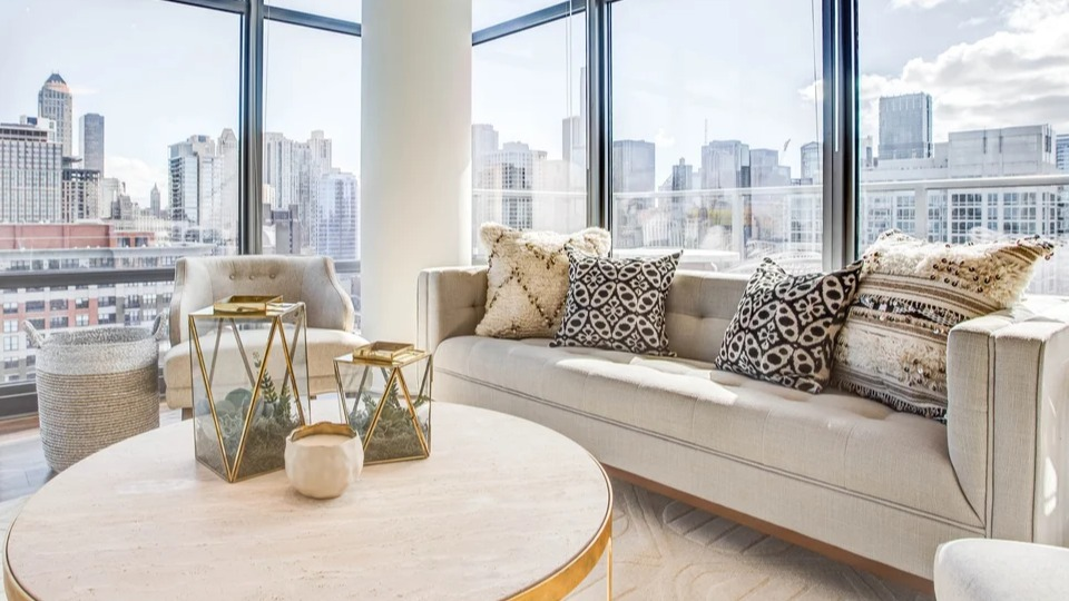 Spacious living room with floor-to-ceiling windows offering stunning city views and comfortable seating at NEXT Apartments in Chicago