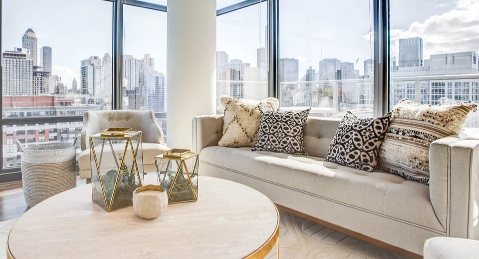 Spacious living room with floor-to-ceiling windows offering stunning city views and comfortable seating at NEXT Apartments in Chicago