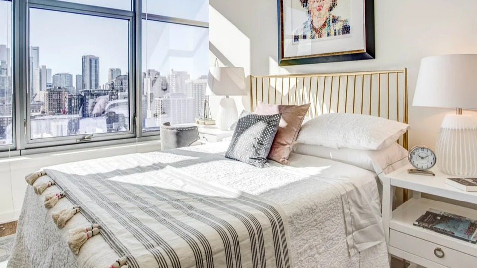 Stylish bedroom featuring a comfortable bed, contemporary art, and large windows with urban views at NEXT Apartments Chicago
